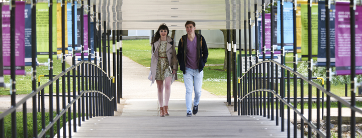 Two students walking across bridge
